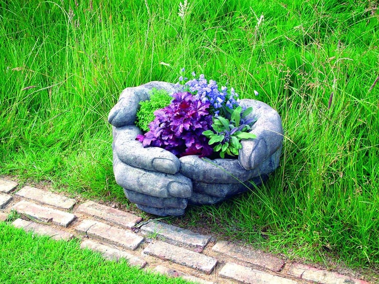 Cupped Hands stone garden planter holding plants in a UK garden