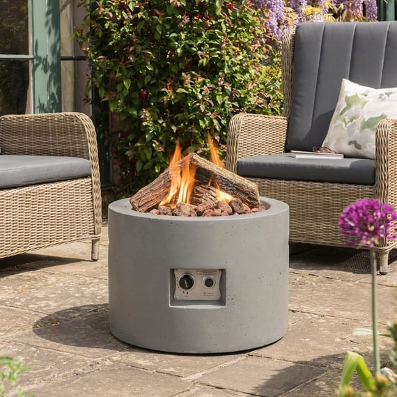 Happy Cocoon 61cm round grey steel fire pit bowl glowing with embers in a UK garden